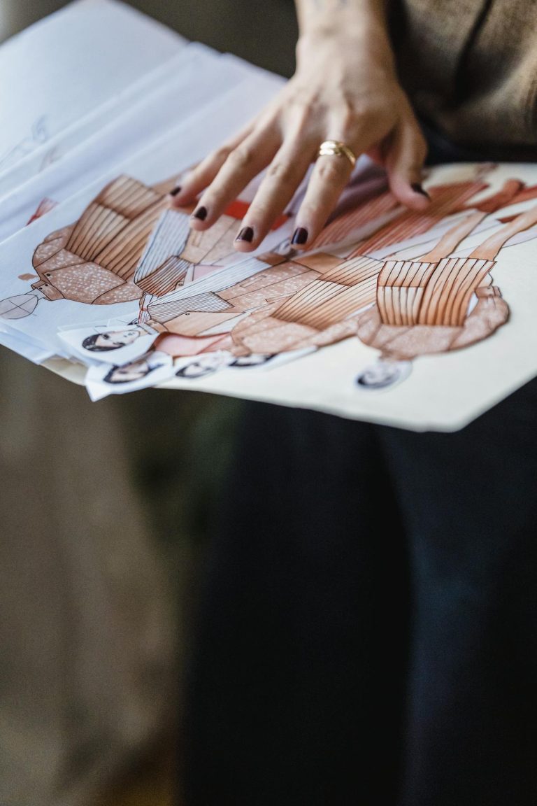Crop dressmaker with folder of fashion illustrations in workshop